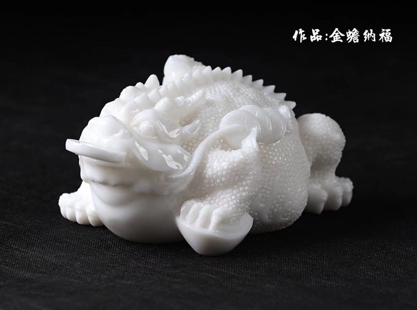 张亚雄雕刻汉白玉金蟾纳福作品的创作理念是将中国传统文化中的神兽一金蟾与福文化相结合，通过现代玉雕艺术